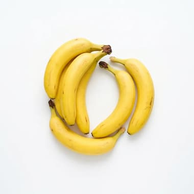 A small bunch of ripe yellow bananas on a plain white background