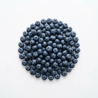 A round pile of fresh blueberries on a plain white background