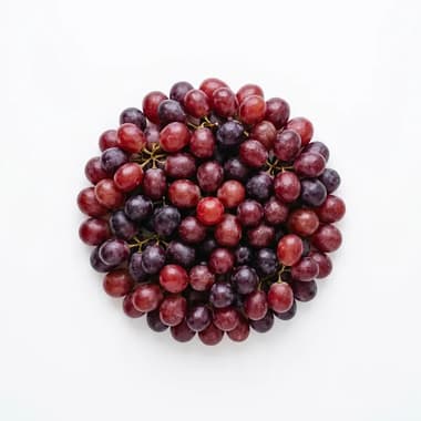 A round pile of red and purple grapes on a plain white background