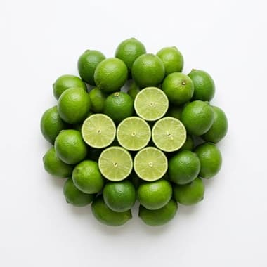 A round pile of green limes with several cut halves, on a plain white background
